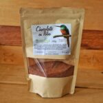 Fotografía de un envase de chocolate en polvo de 200g, elaborado con cacao 100% natural infusionado con clavos y canela