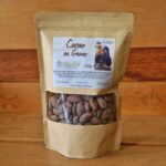 Bolsa de semillas de cacao tostadas de 250g, colocada sobre una superficie rústica con granos de cacao alrededor.